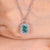 Radiant cut cyan blue moissanite halo pendant.
