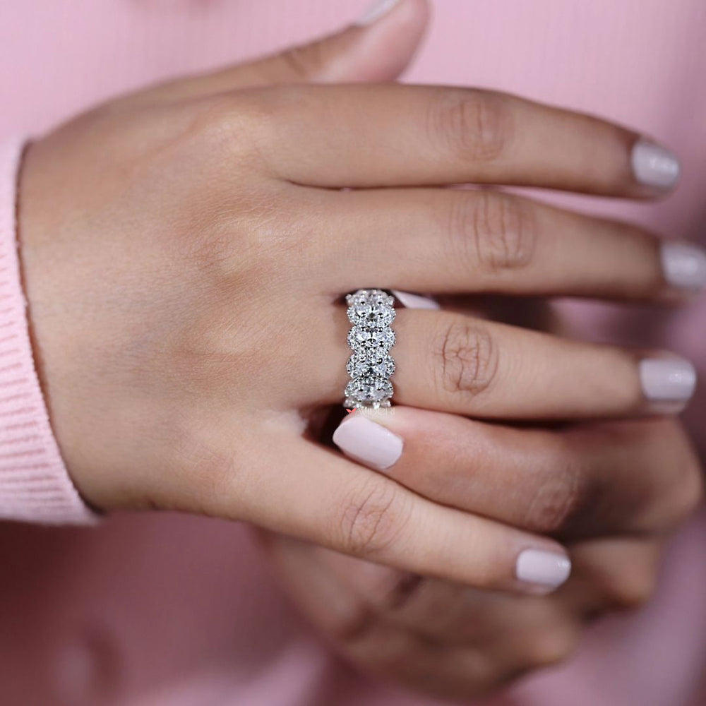 Oval cut wedding band with round moissanite halo accents.