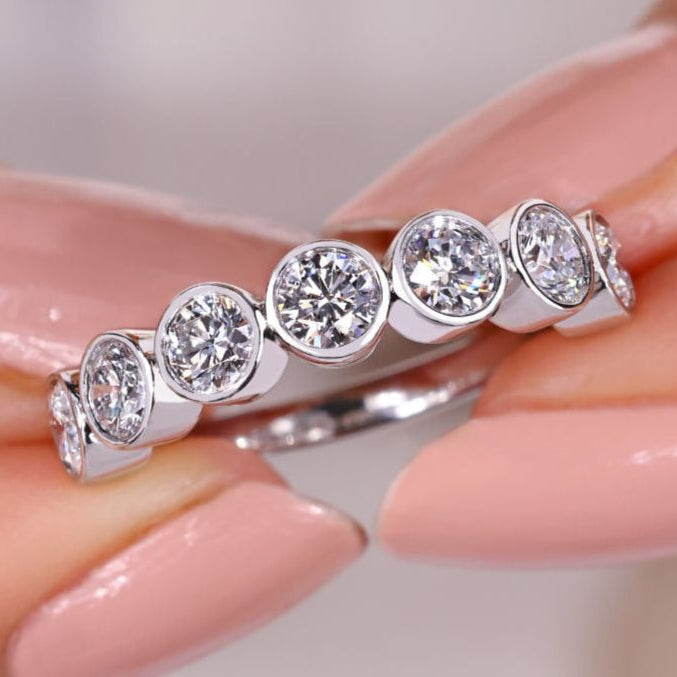 Bezel set diamond band in white gold with round cut stones.
