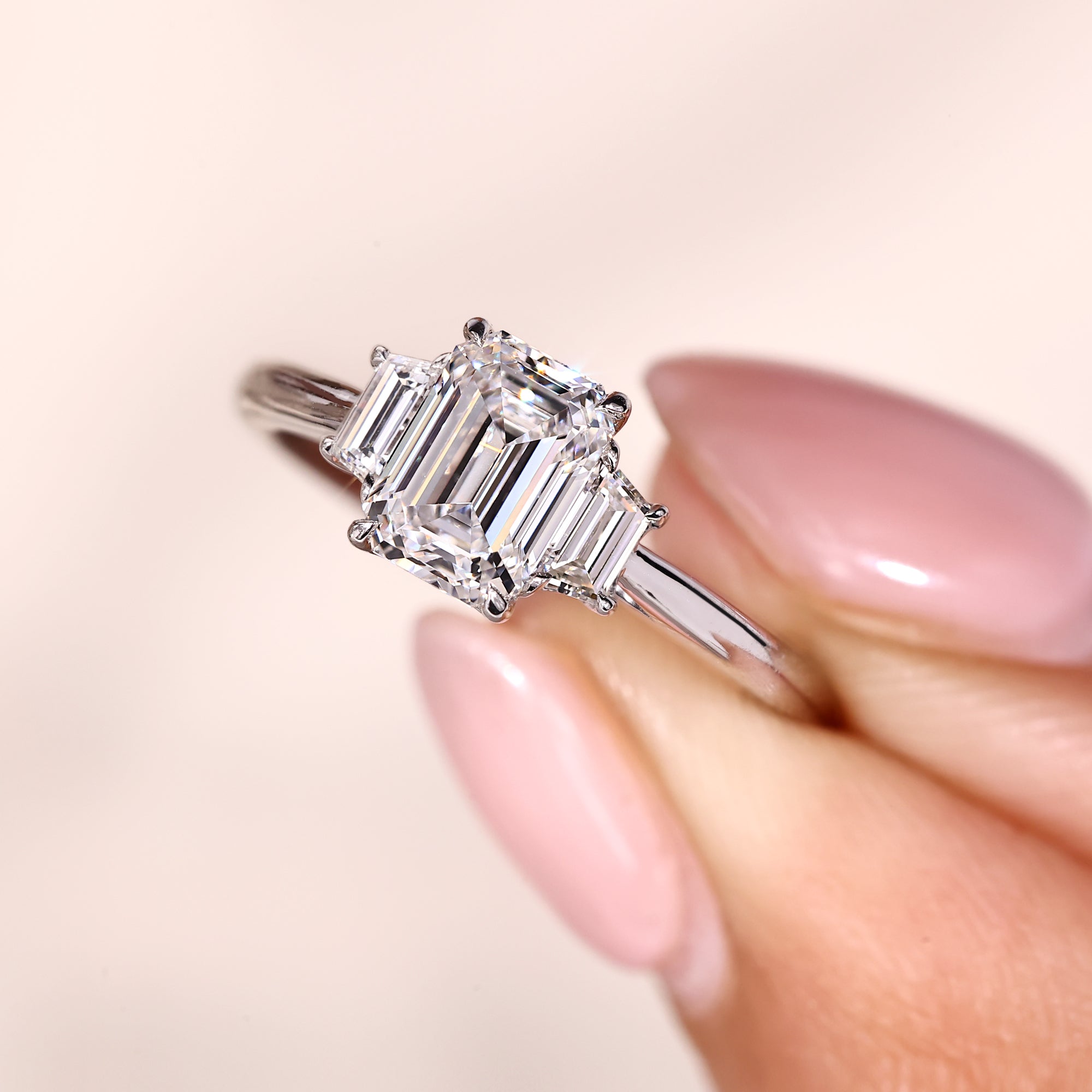 3 stone ring with tapered shank and trapezoid step cut side stones.