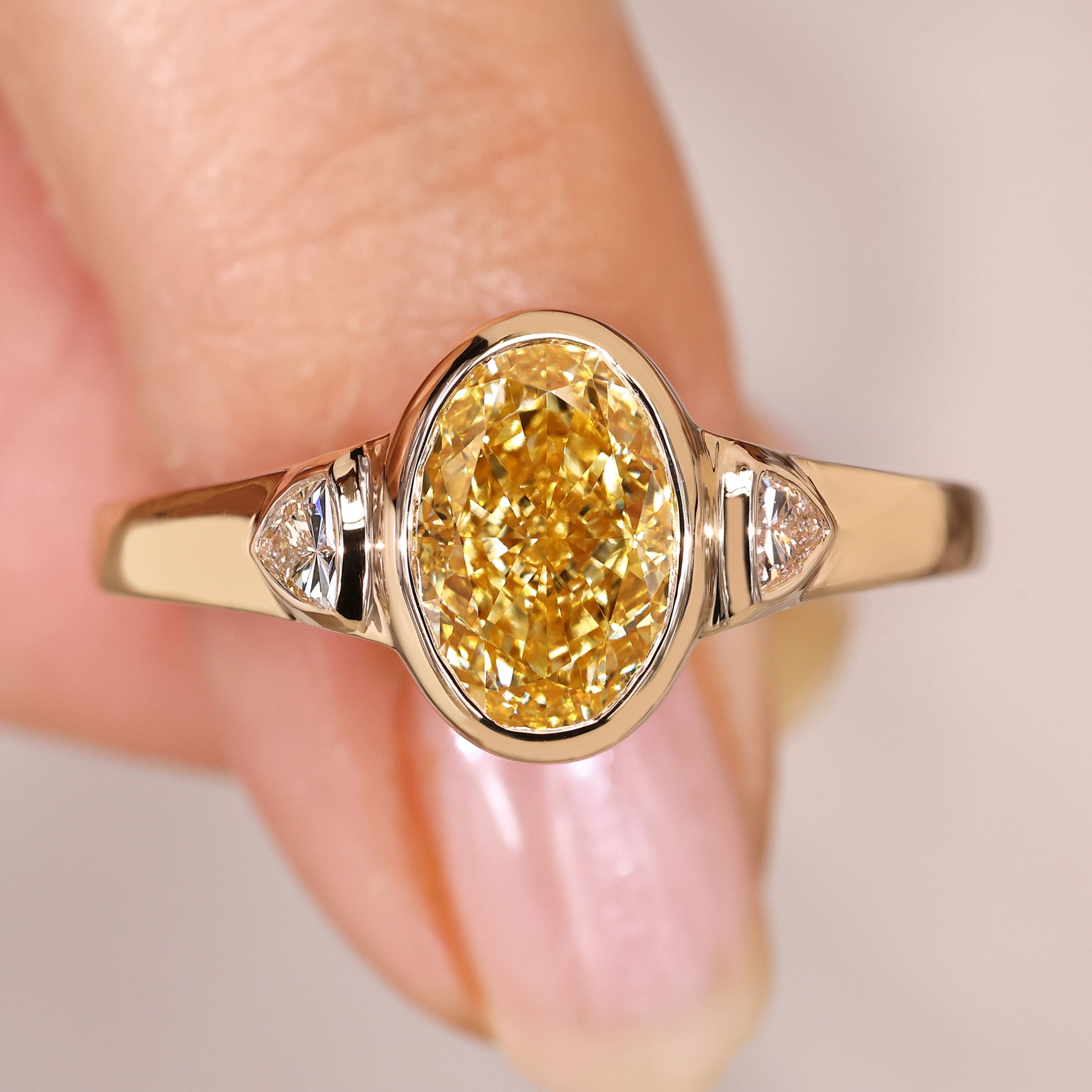 Oval cut yellow diamond ring with trillion sides.
