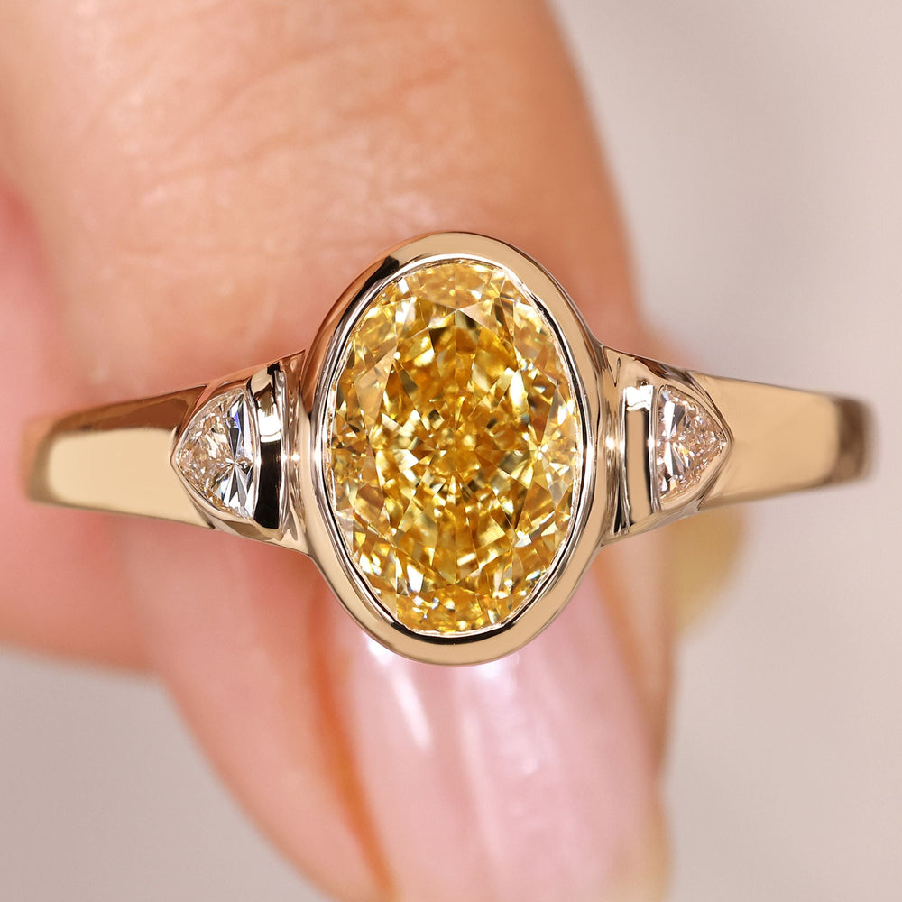 Oval cut yellow diamond ring with trillion sides.
