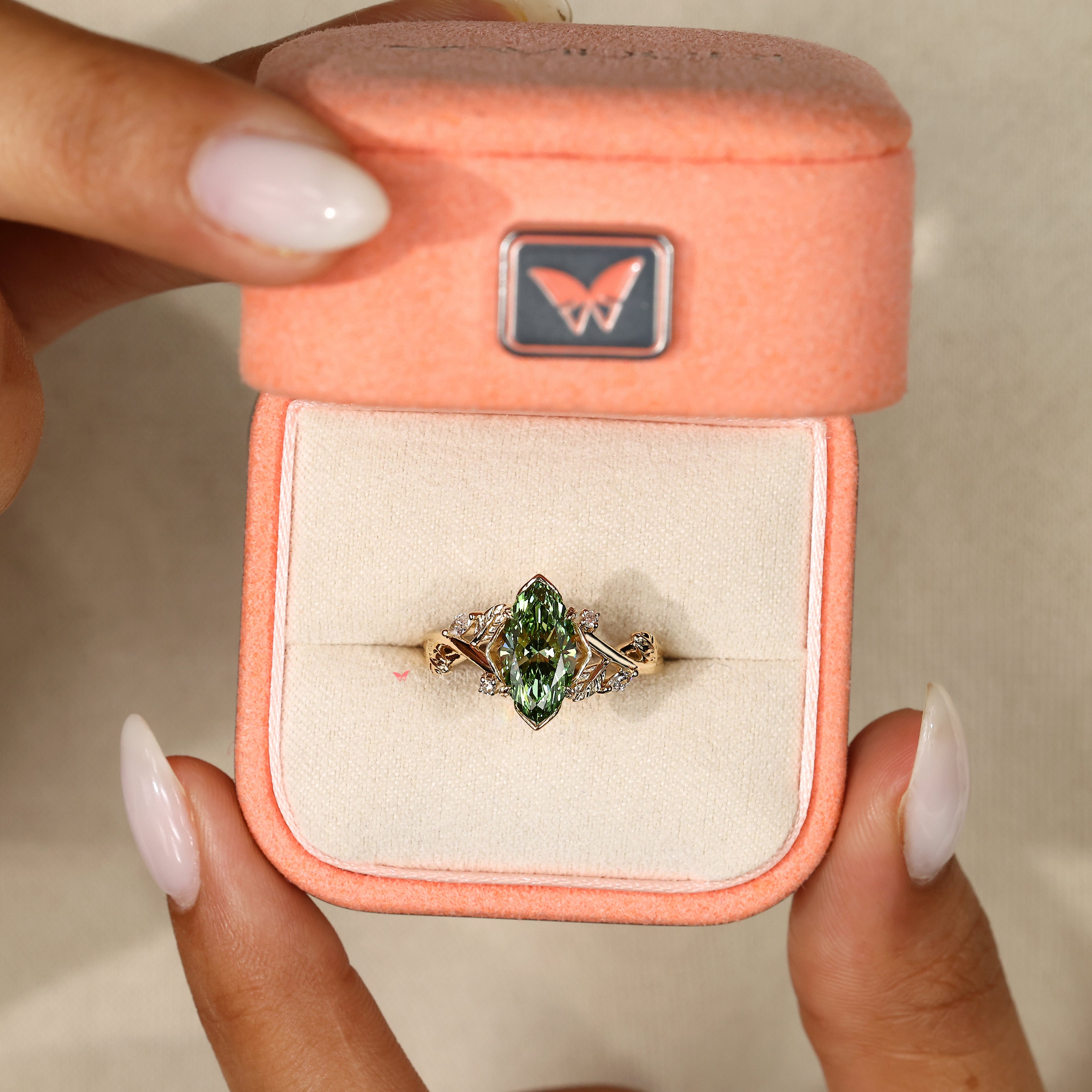 Green marquise diamond ring with botanical detail.
