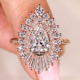 Pear cut diamond ring with tapered baguette and round halo.
