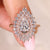 Pear cut diamond ring with tapered baguette and round halo.