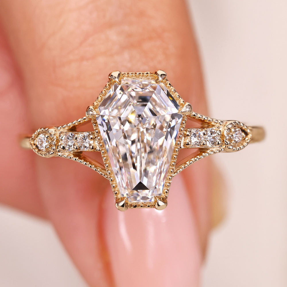 Elongated shield cut diamond ring with round side stones.
