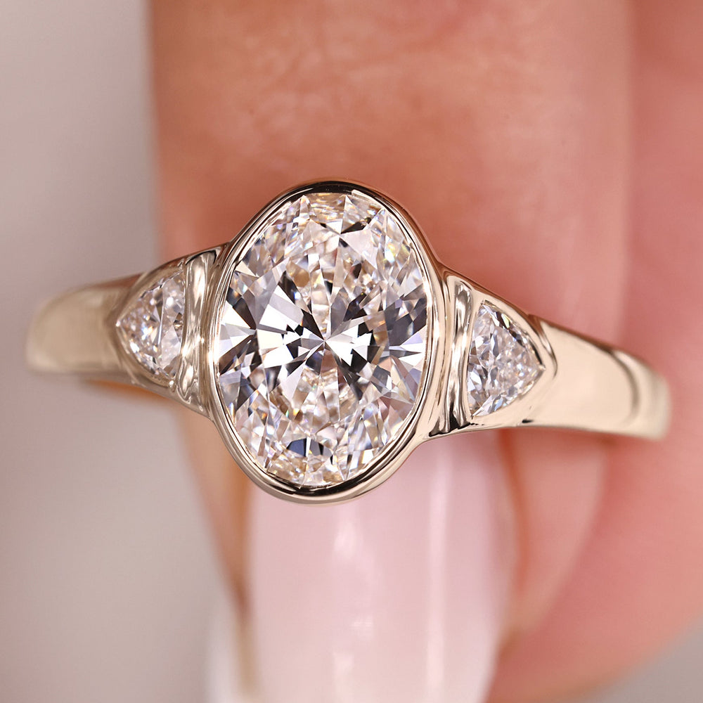 Three stone engagement ring with oval center diamond.