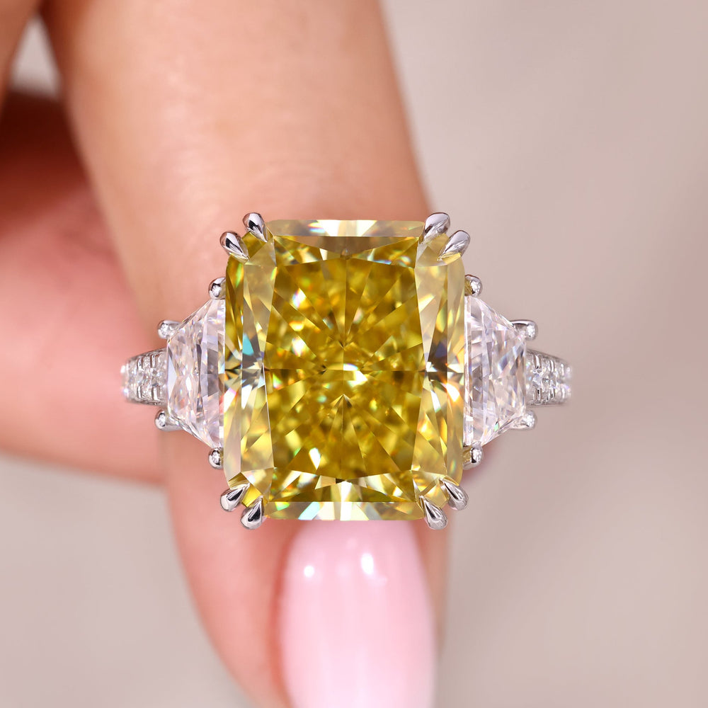 Ring with a yellow gemstone held by a hand against a neutral background