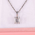 Emerald solitaire pendant in white gold with claw prong setting.