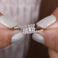 A baguette engagement ring placed on a white display.
