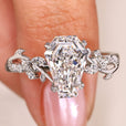Coffin Diamond ring held by a hand with a soft pink background