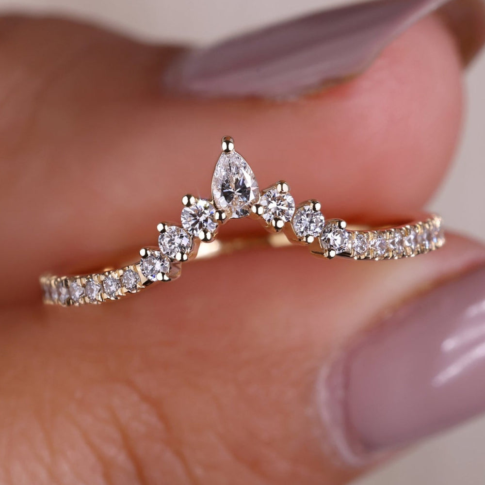 An image of a hand holding a delicate pear shaped lab grown diamond half eternity band ring.