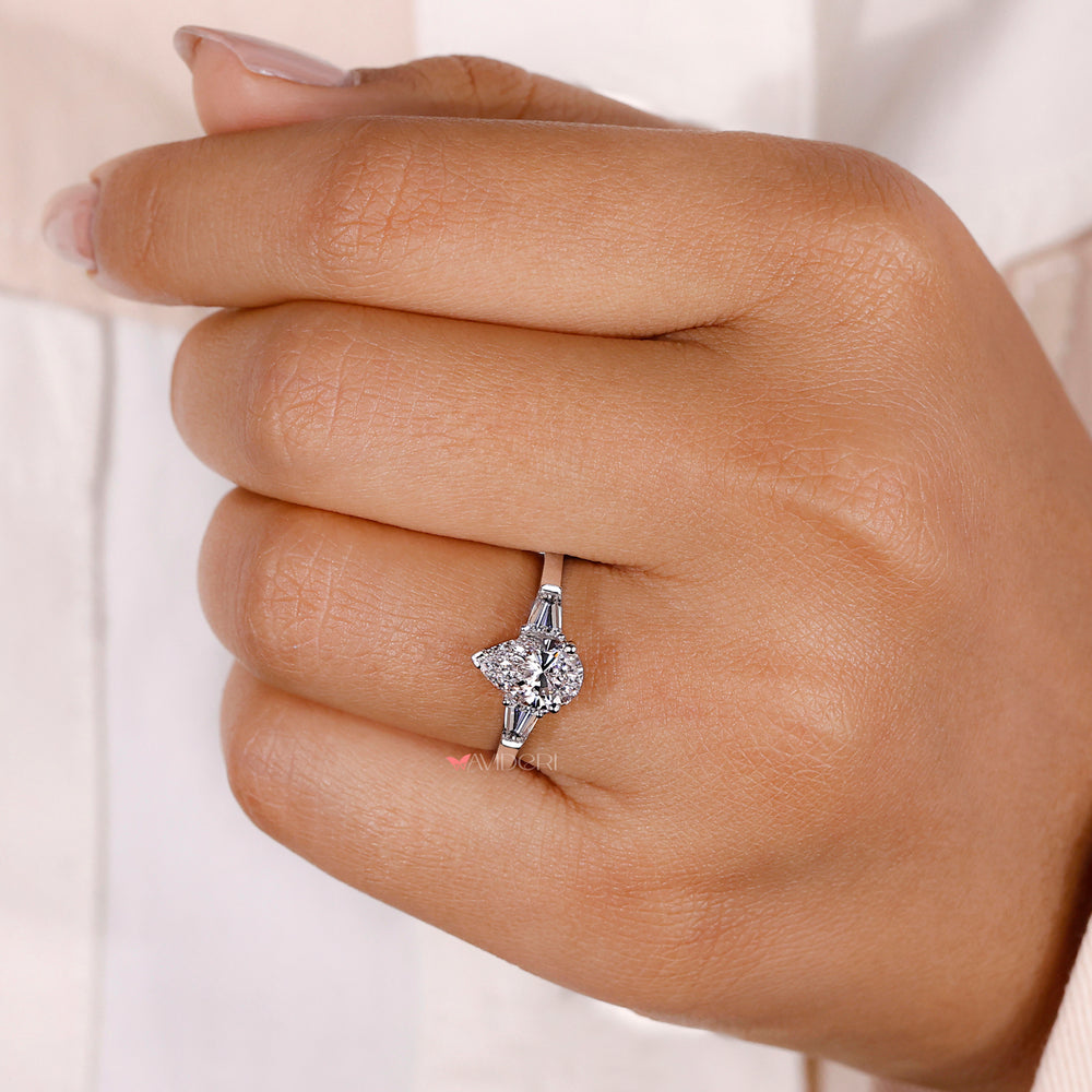 3 ring diamond showcasing a pear-shaped centerpiece surrounded by brilliant accents, ideal for timeless engagement styles.
