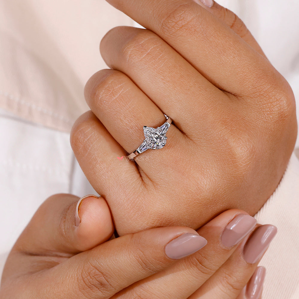 3 stone diamond ring combining a pear-shaped center stone with complementary side diamonds for added sparkle and elegance.
