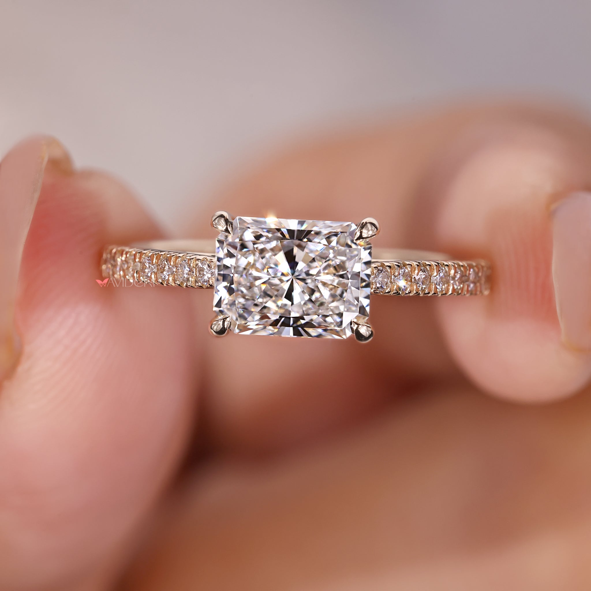 Radiant cut diamond engagement ring with pave round diamonds.