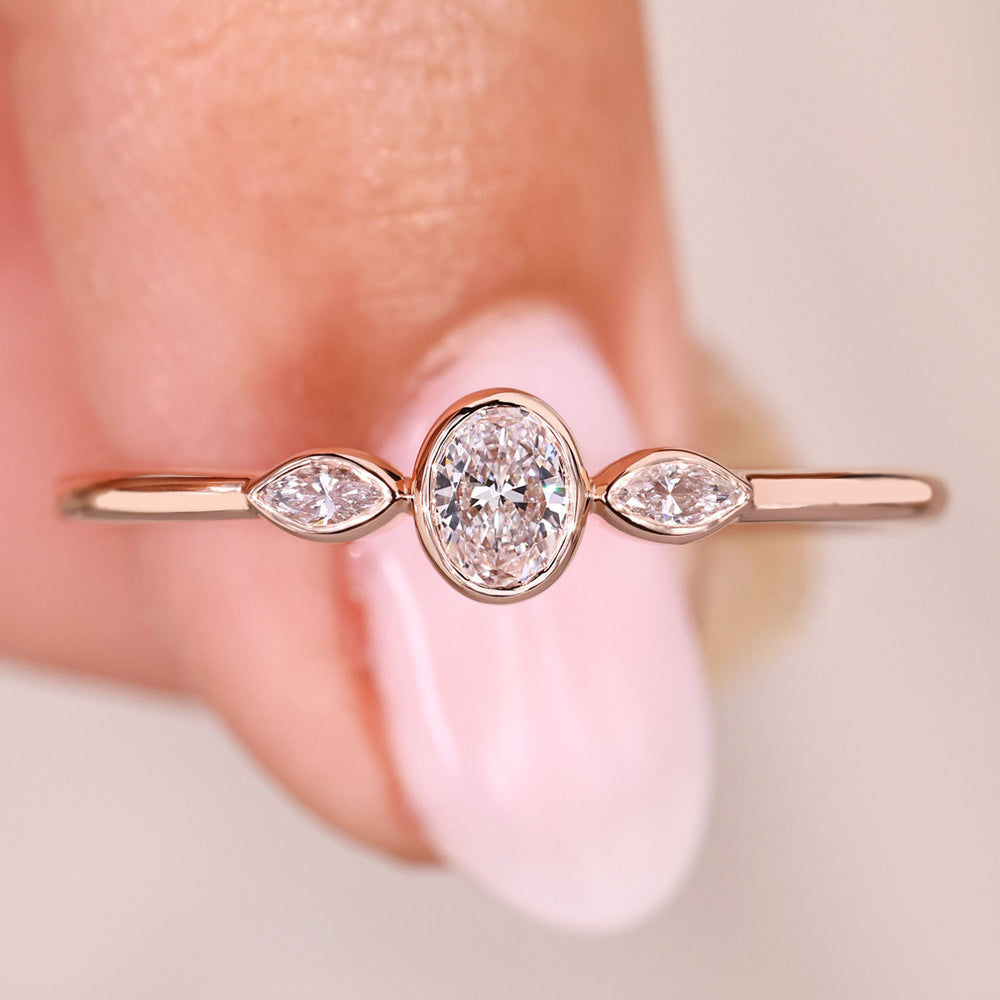 Three stone ring with oval cut center diamond and marquise sides.
