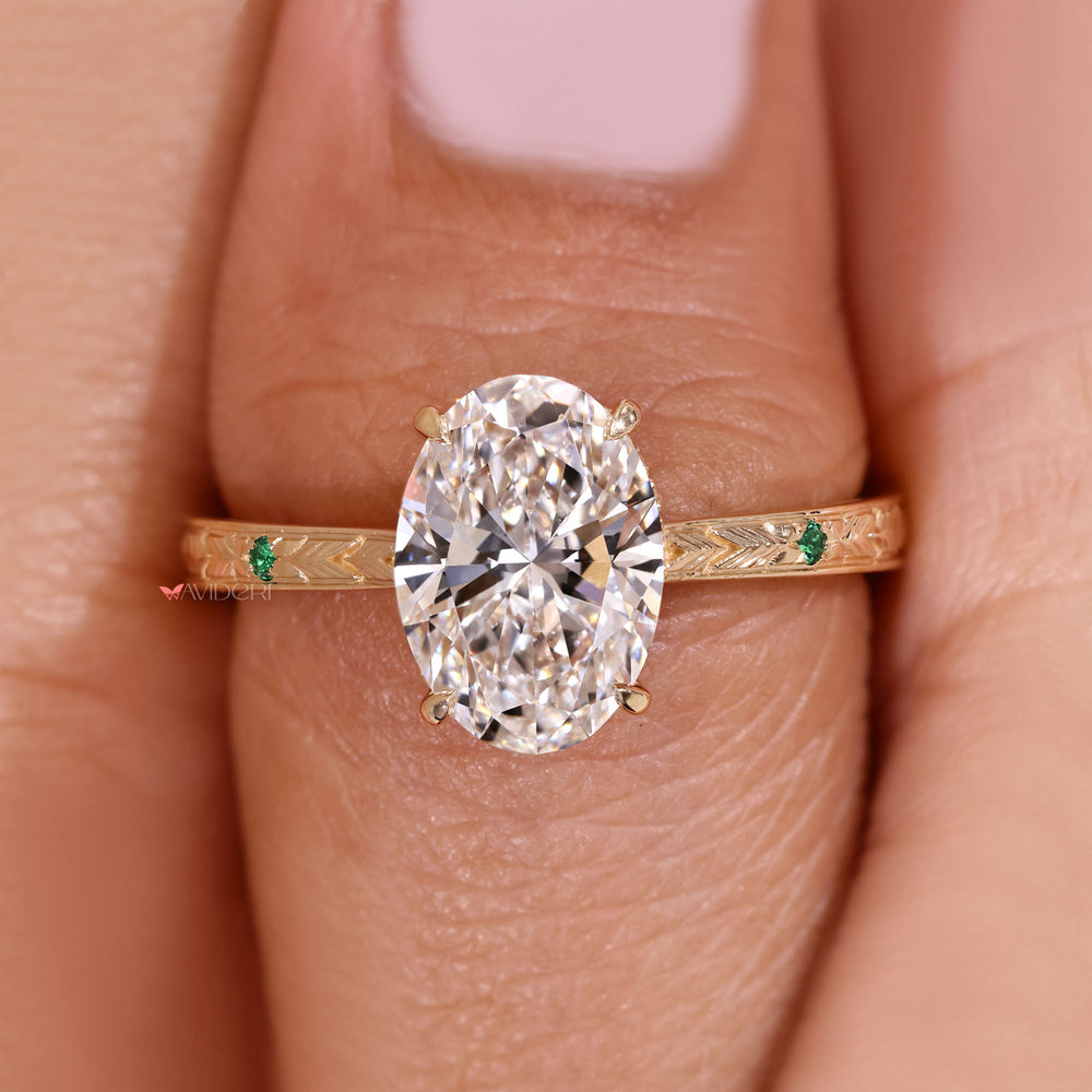 Oval cut diamond ring with emerald side accents.
