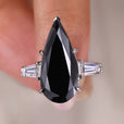 elongated pear cut engagement ring with tapered baguette side stones in white gold.