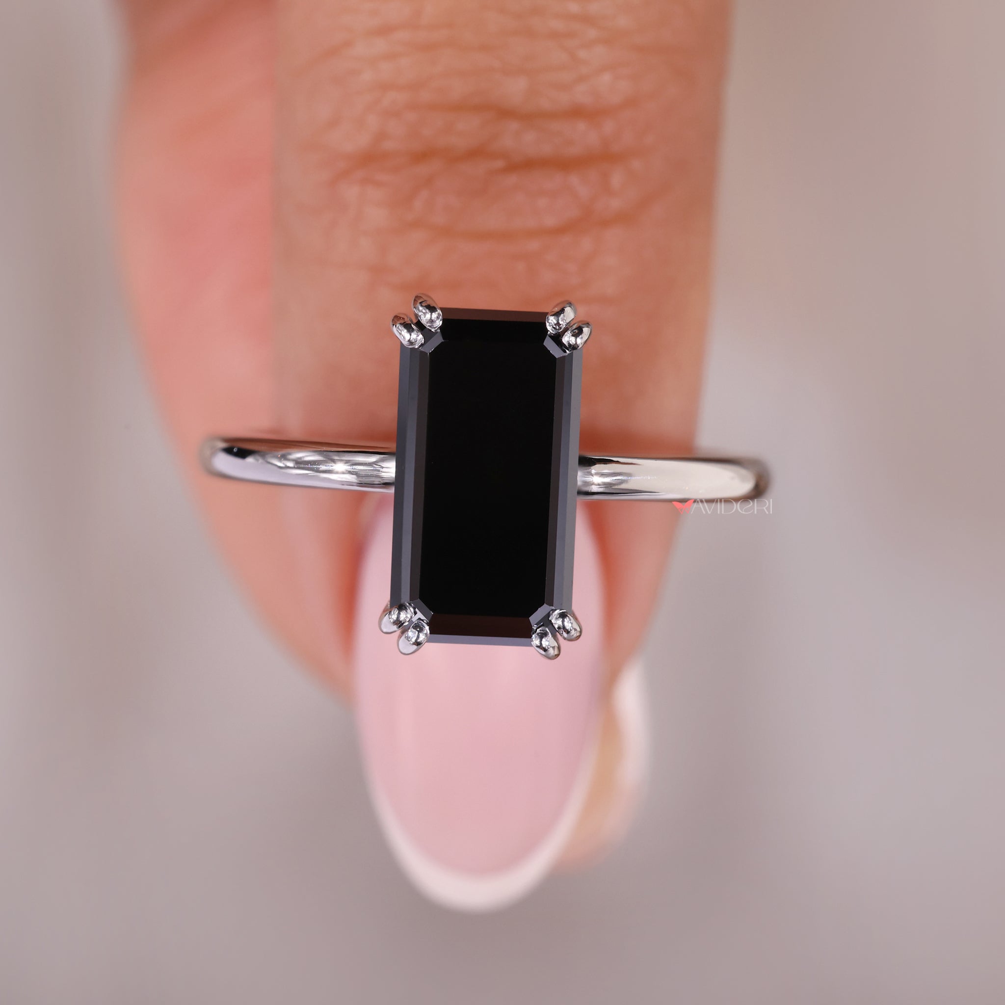 Double prong ring holding an elongated emerald stone
