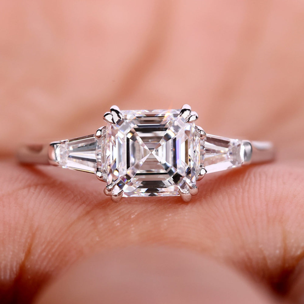 An Image of a hand showing a three stone engagement ring.