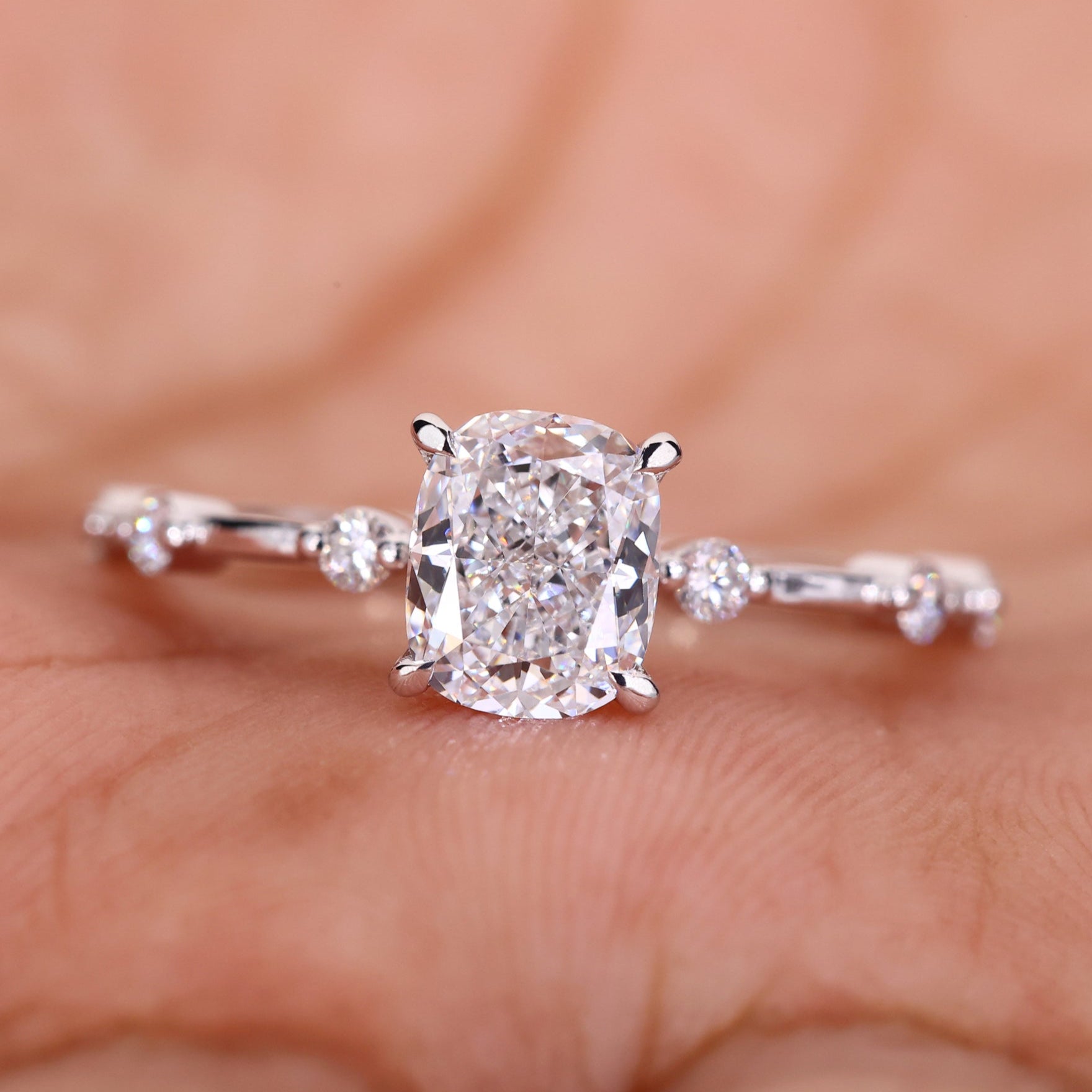 Elegant cushion cut engagement ring featuring a Lab Grown Diamond with a claw prong setting and Distance Pave Setting.

