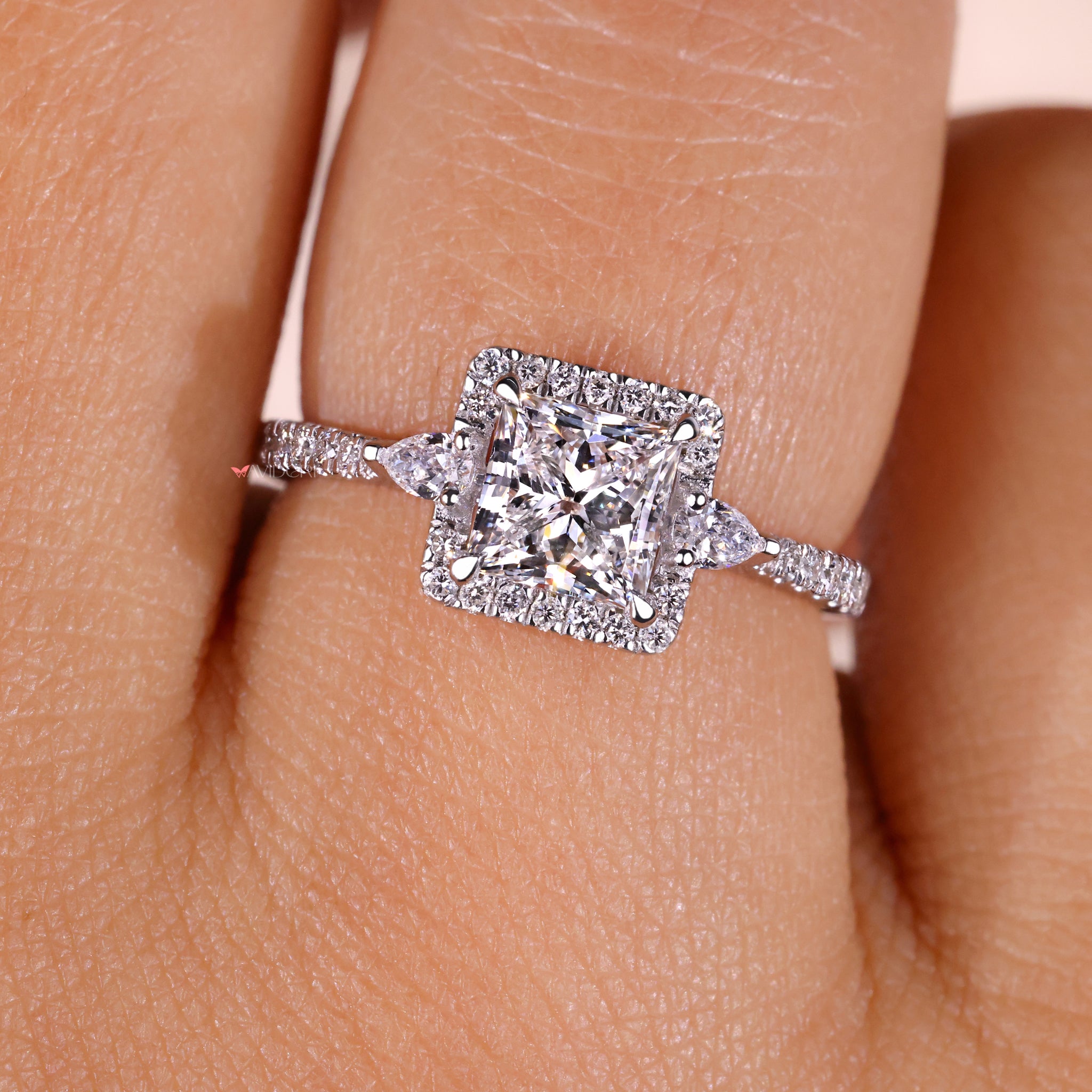 Engagement ring with 2 pear cut side stones and a central princess diamond, offering a unique and luxurious design.

