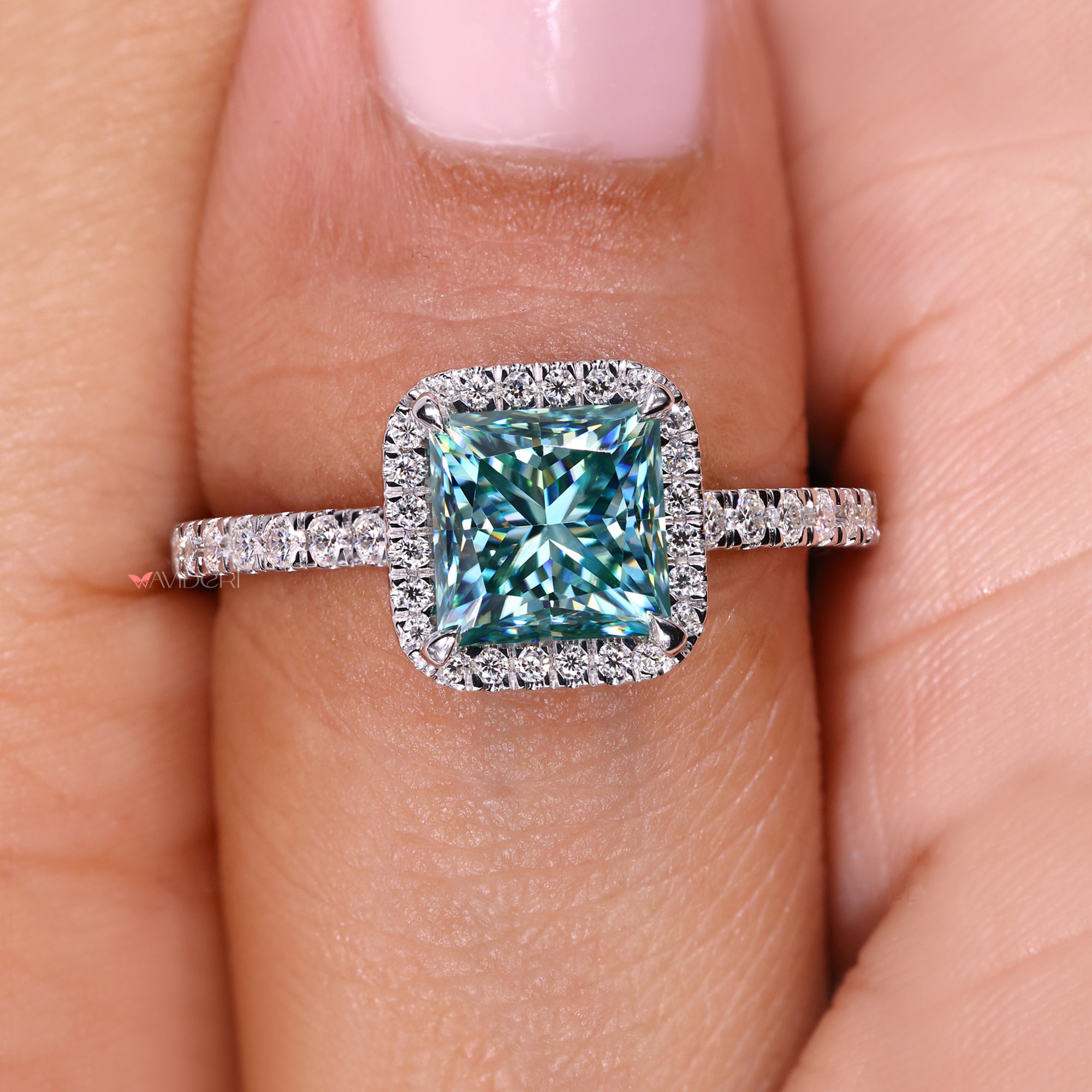 Ring with a blue moissanite on a finger.