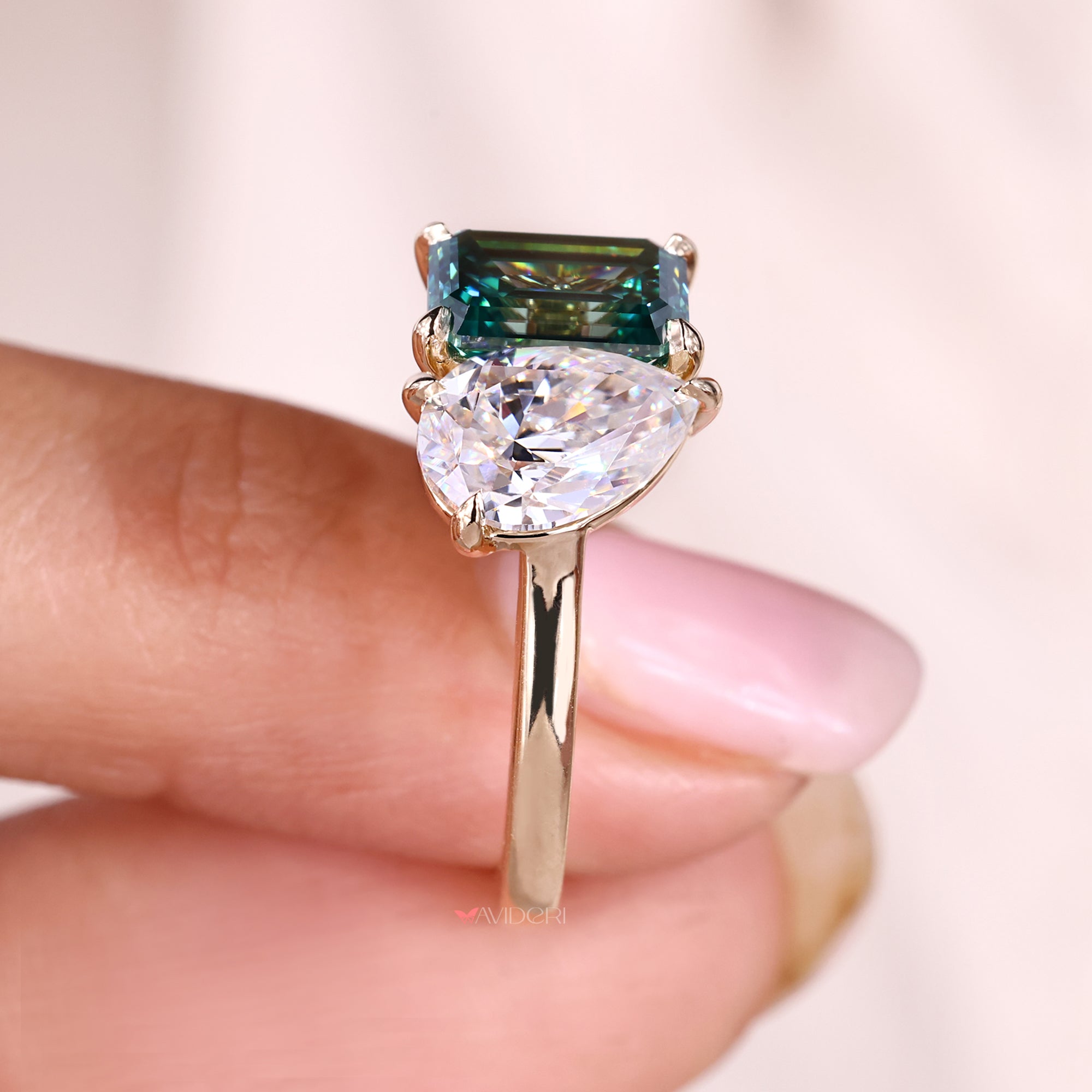 Yellow gold ring with pear and emerald cut moissanite stones.