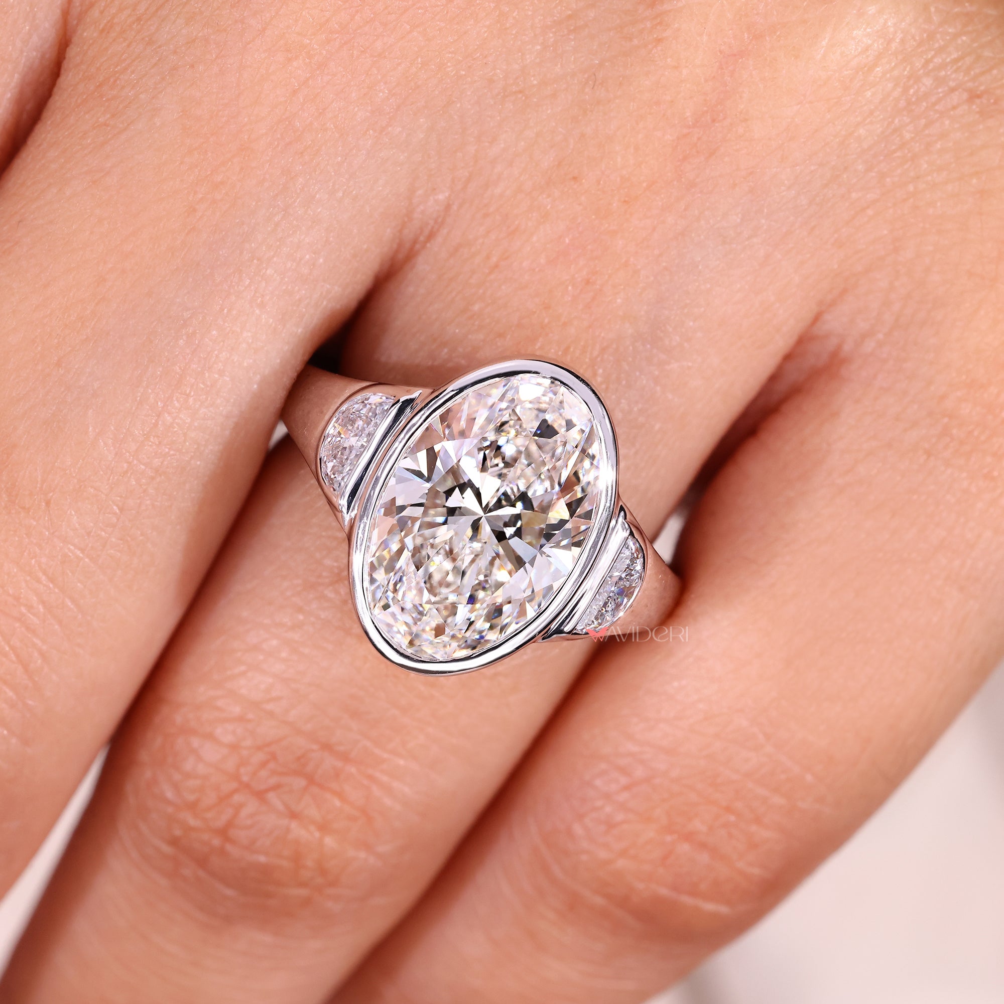 Oval cut center diamond three stone ring with bezel setting.