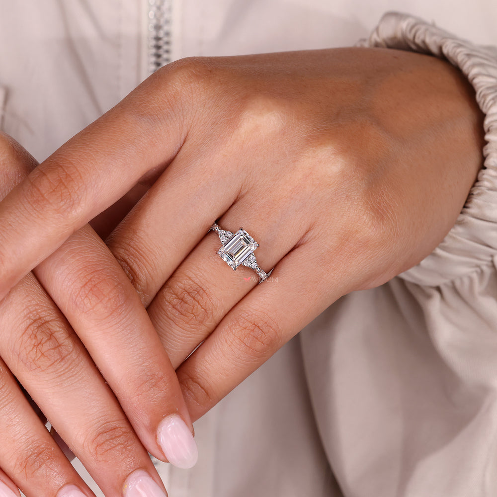 Emerald cut diamond ring with four claw prongs.
