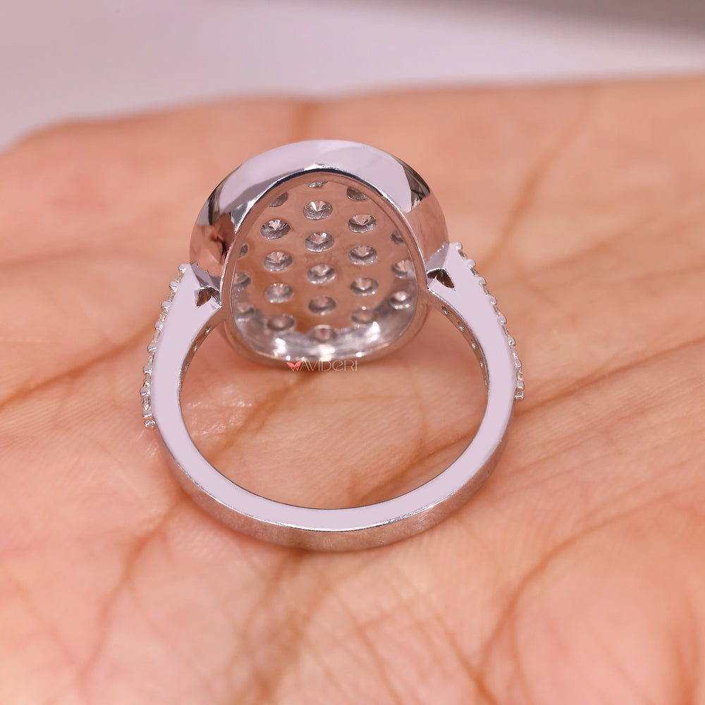 Round diamond ring with oval outline and pave accents.
