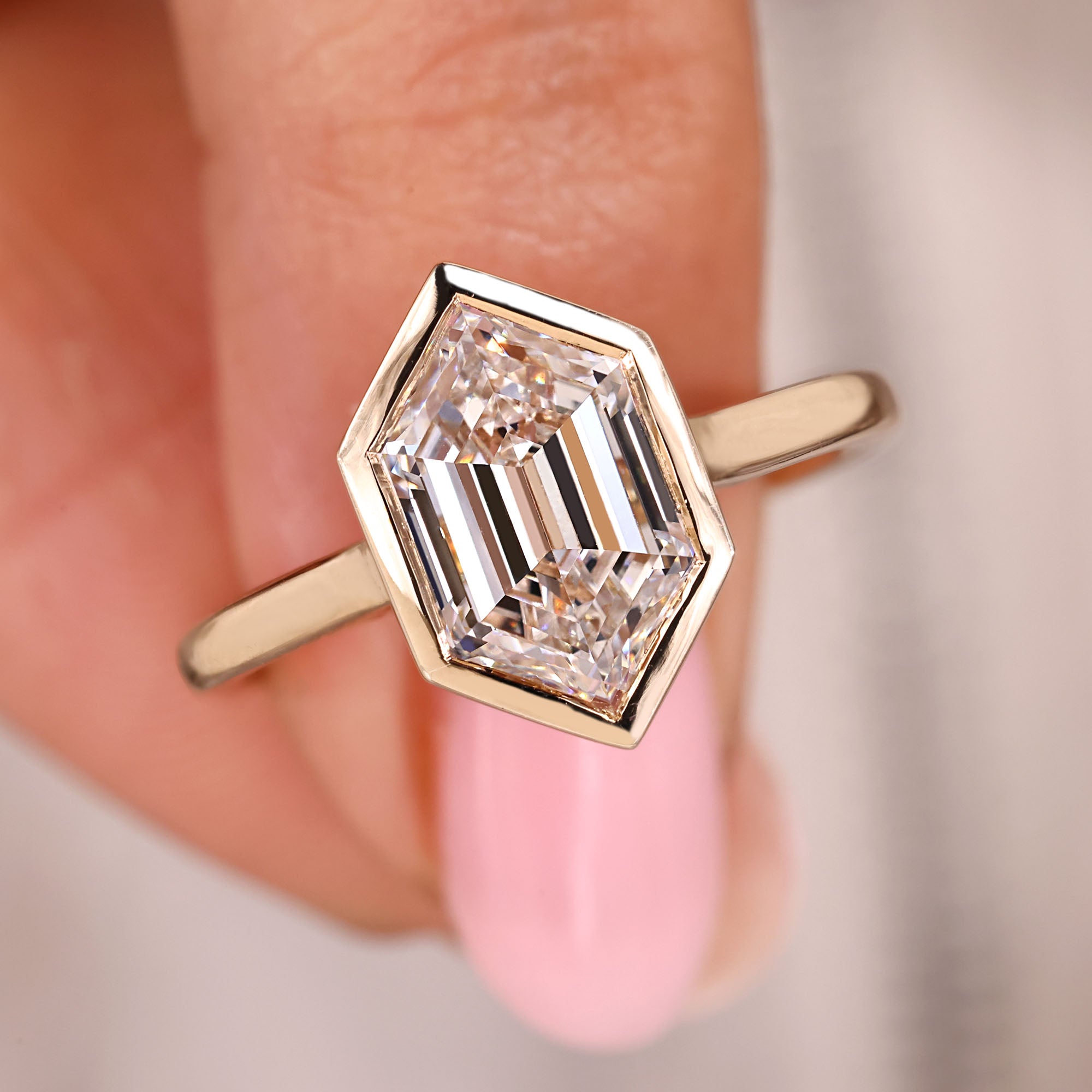 Hexagon cut engagement ring with bezel setting in yellow gold.