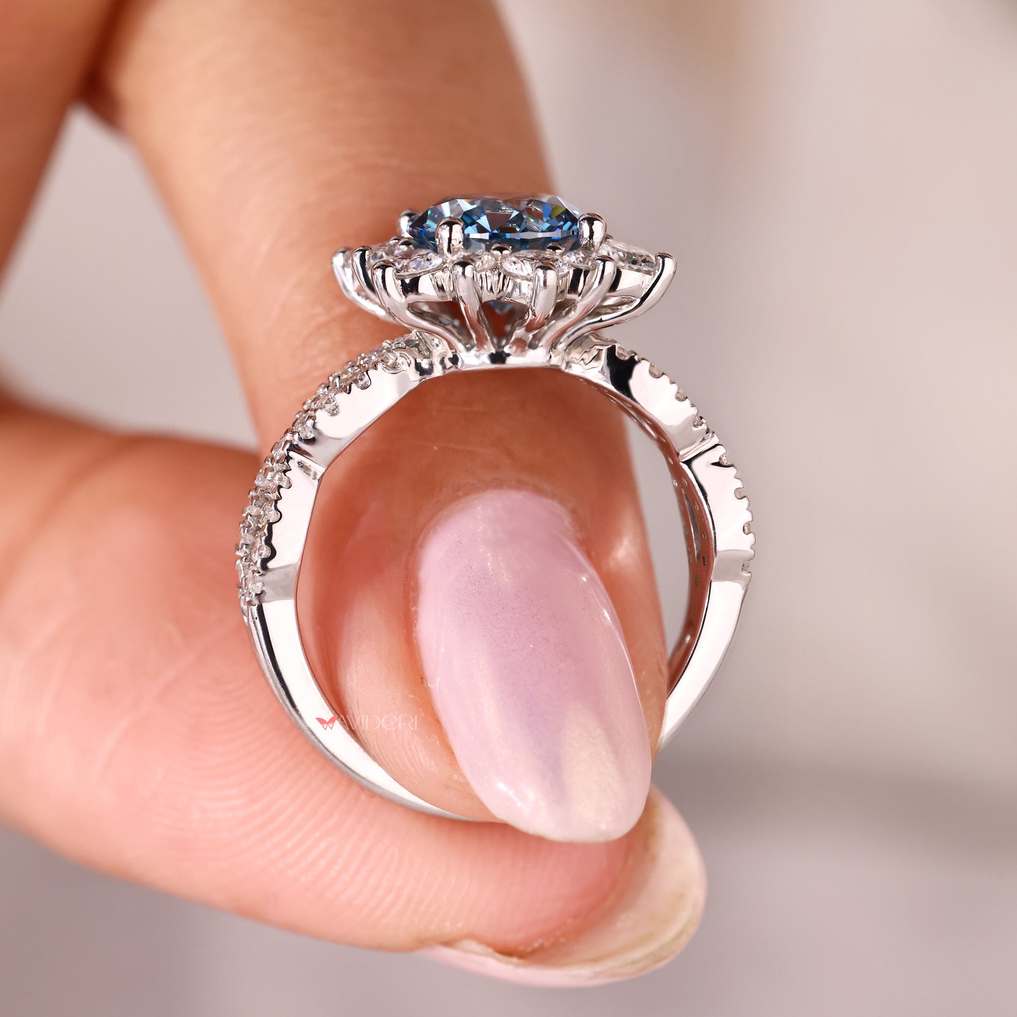 white gold round blue diamond ring with floral design and cluster setting.