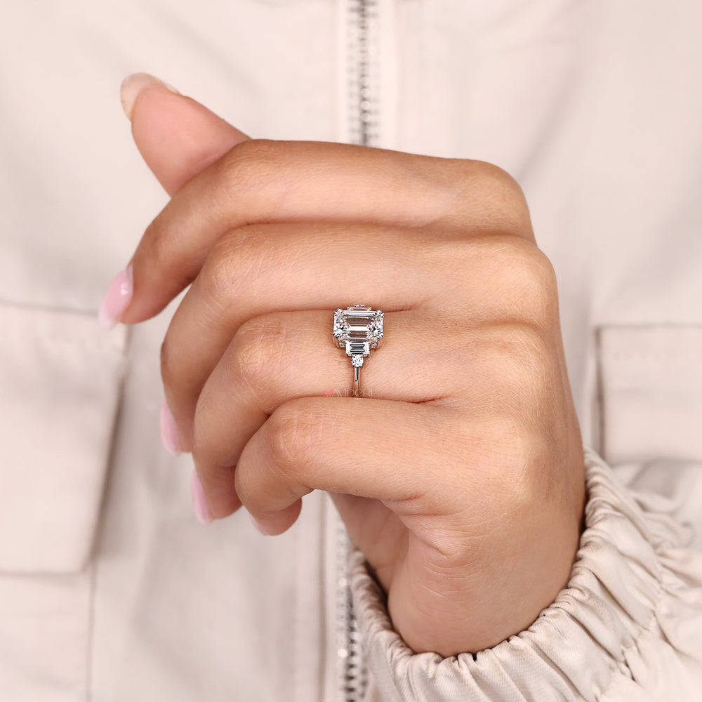 Five stone ring with emerald center and round accents.
