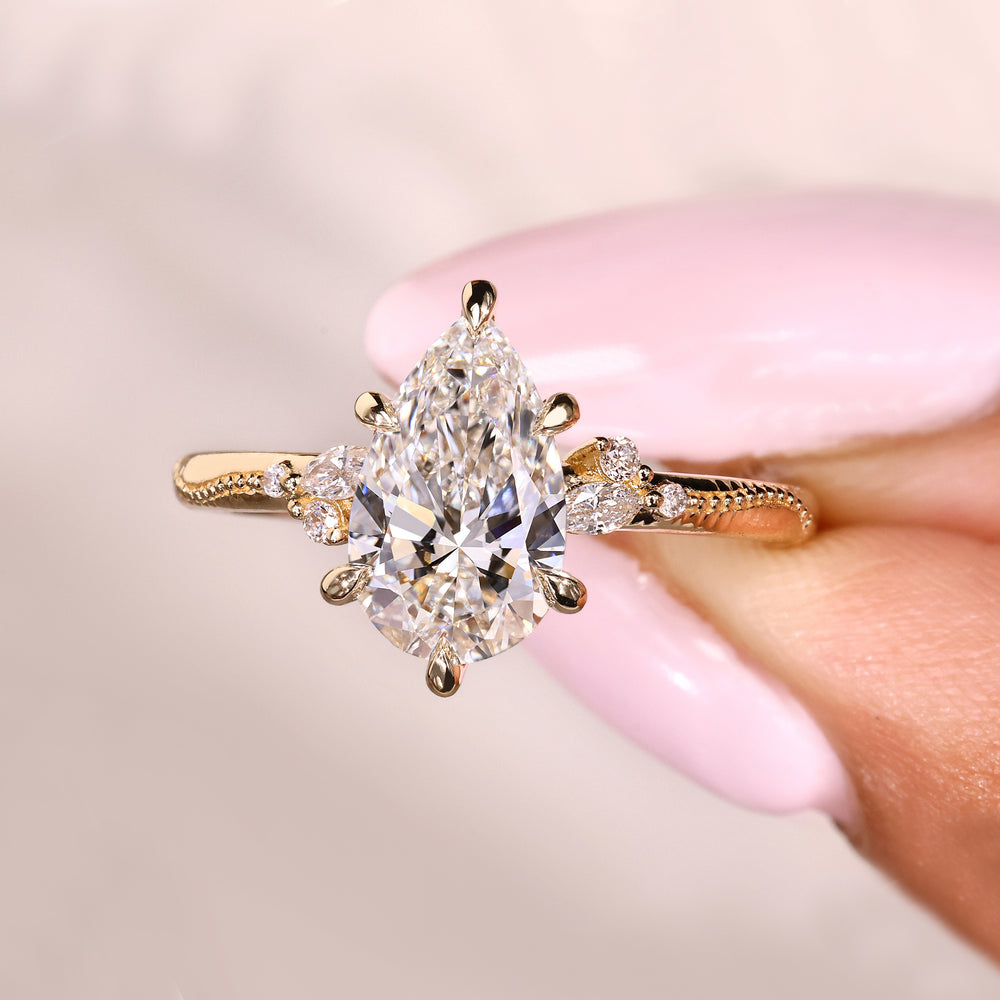 Vintage pear cut diamond ring with round side accents
