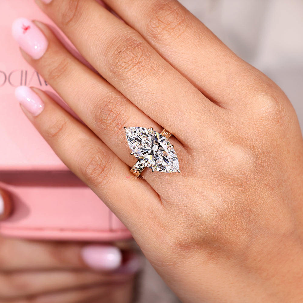 Close-up of a hand wearing a diamond ring with a pink background.