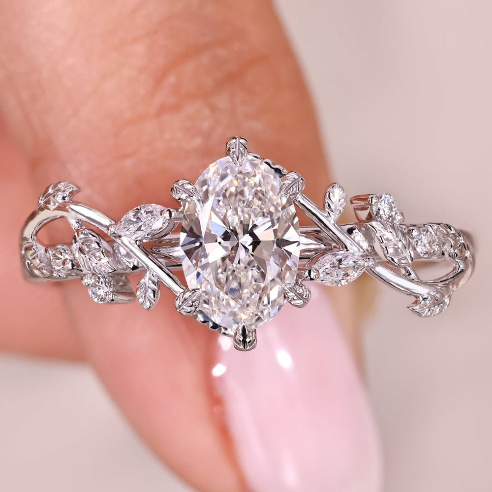 Oval cut diamond ring with nature inspired design and side diamonds.
