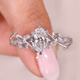 Oval cut diamond ring with nature inspired design and side diamonds.
