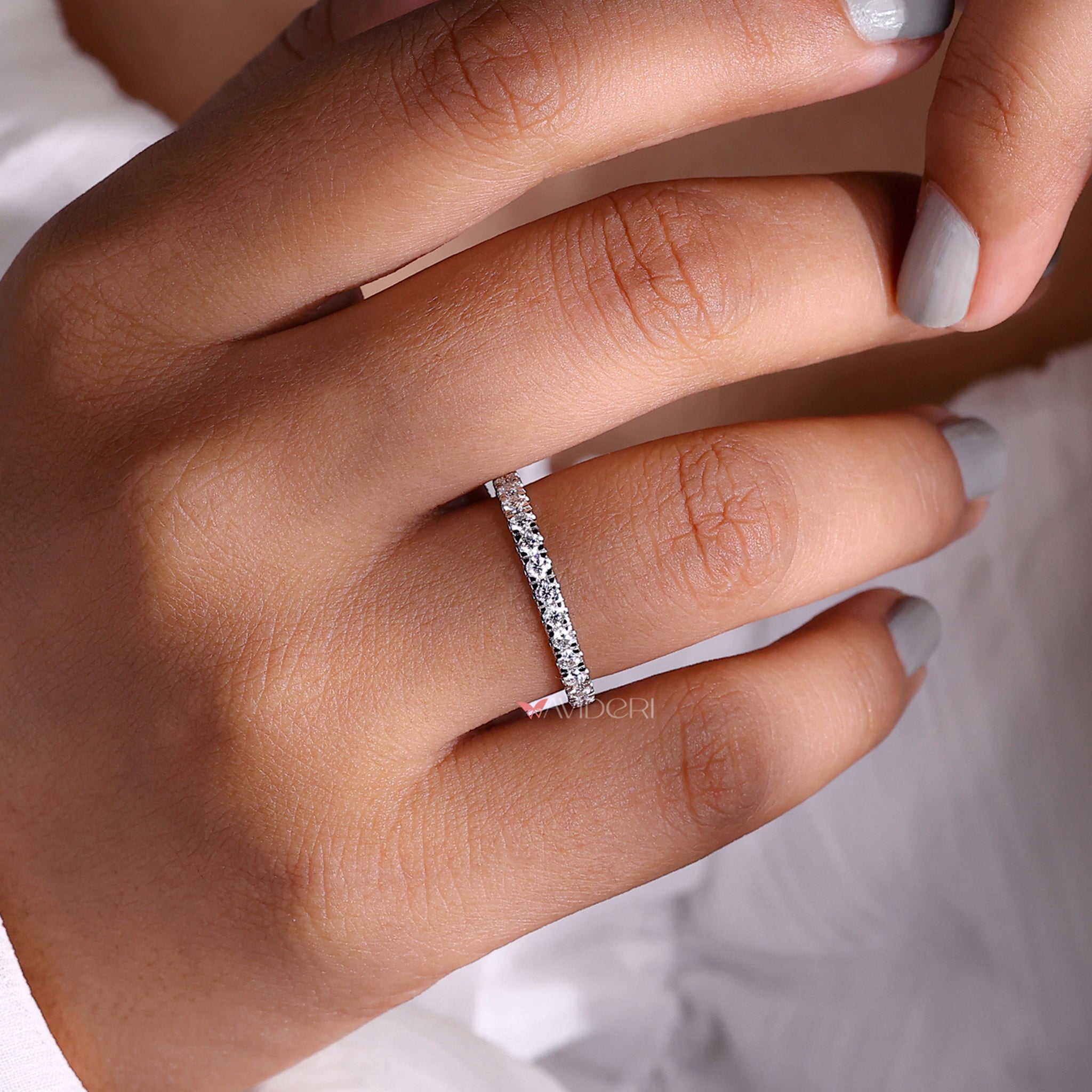 White gold eternity band featuring a continuous row of diamonds.
