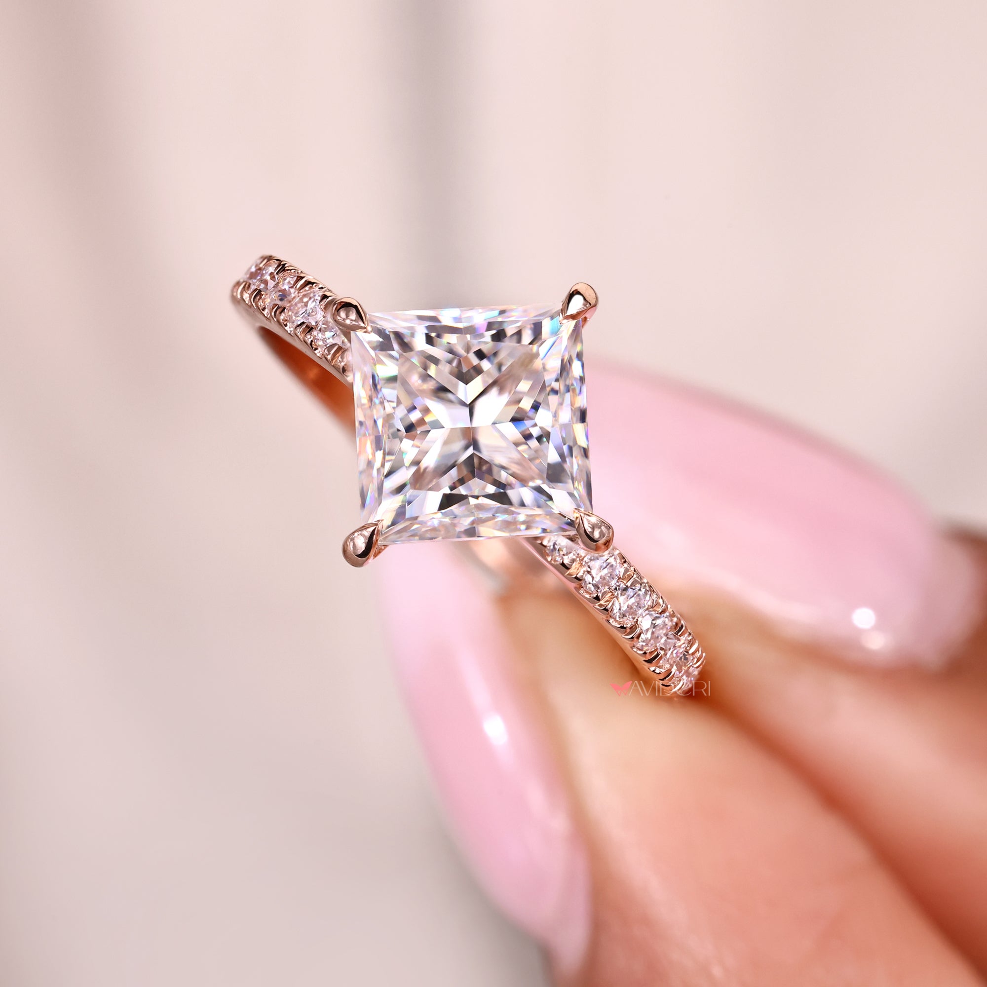 Square cut moissanite ring with compass-style prongs and pave shank.