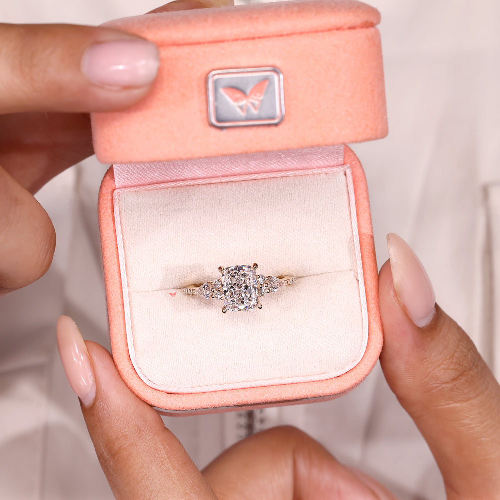 Cushion diamond ring with round and kite side accents.
