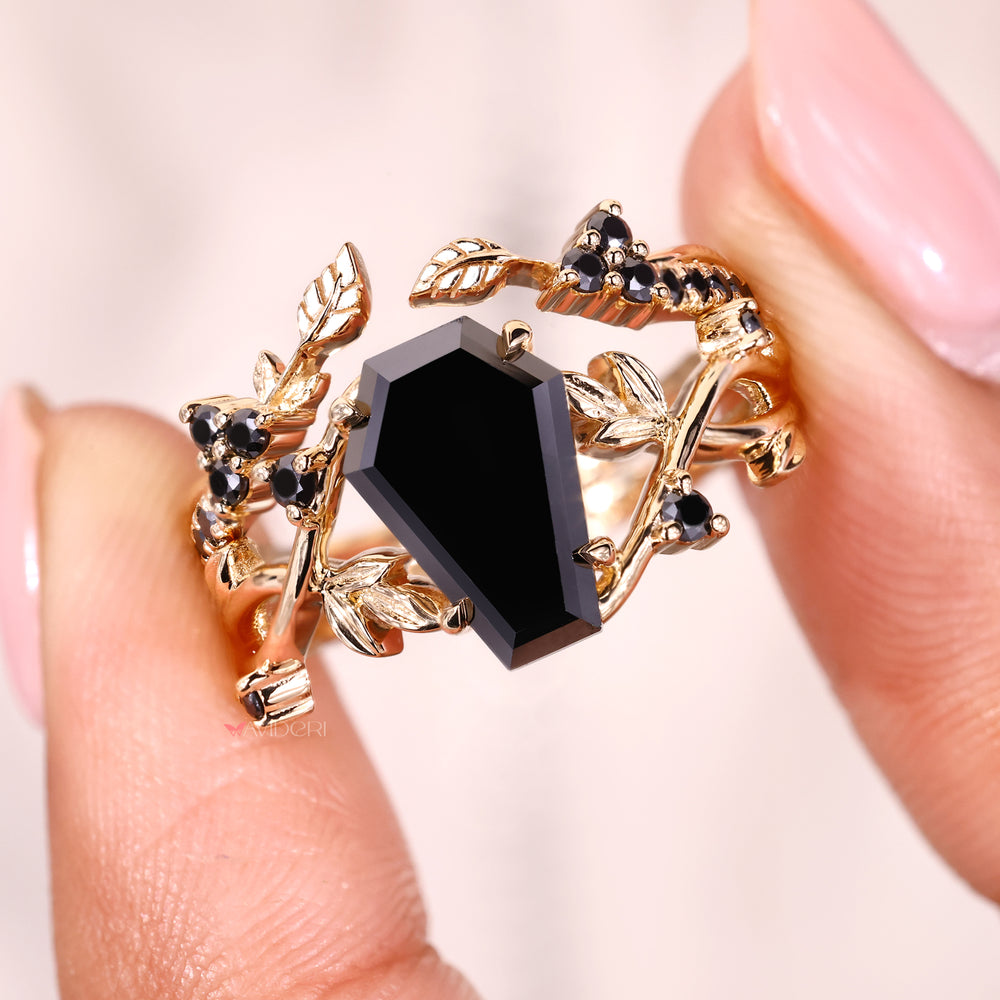 Coffin cut black moissanite set in a detailed yellow gold design.