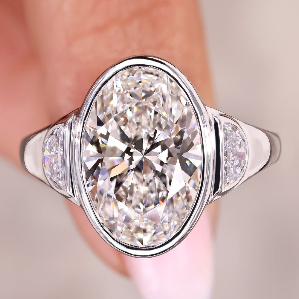 Three stone engagement ring with oval cut center diamond.