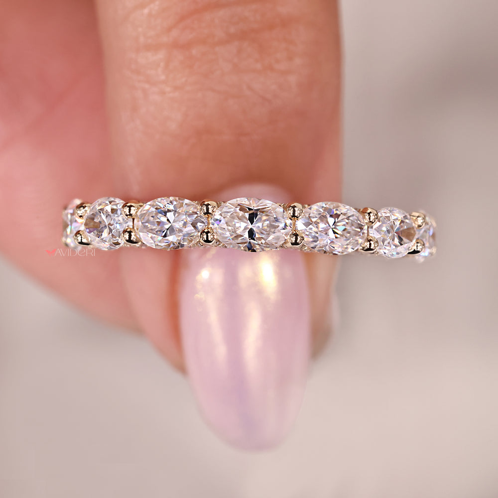 Prong set wedding band made with oval and round moissanite stones.