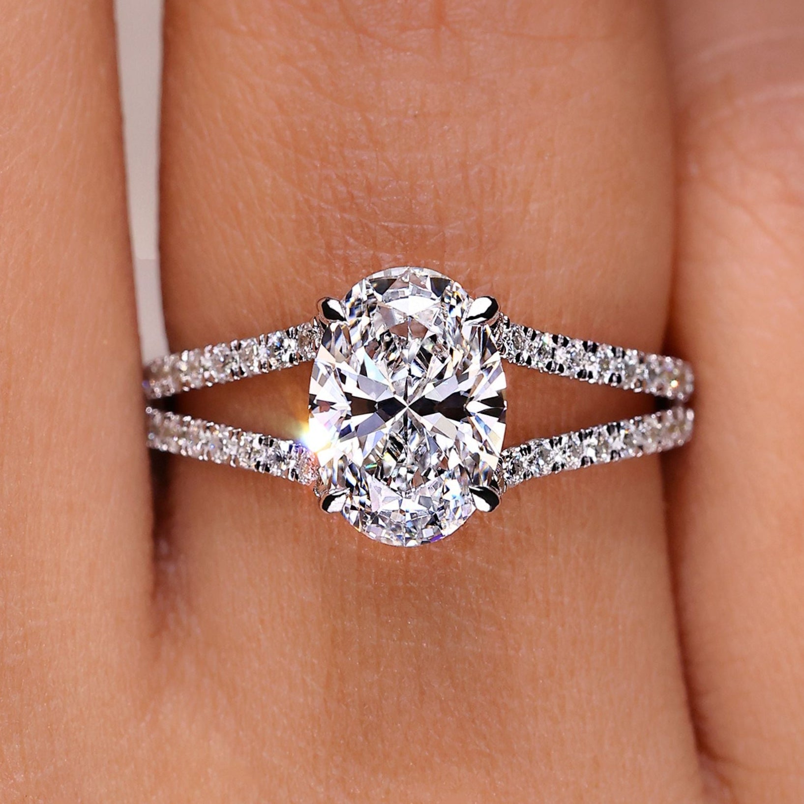 Oval cut diamond ring with hidden halo and split pave band.
