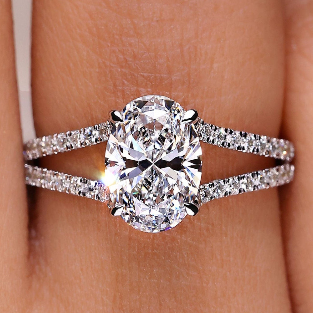 Oval cut diamond ring with hidden halo and split pave band.
