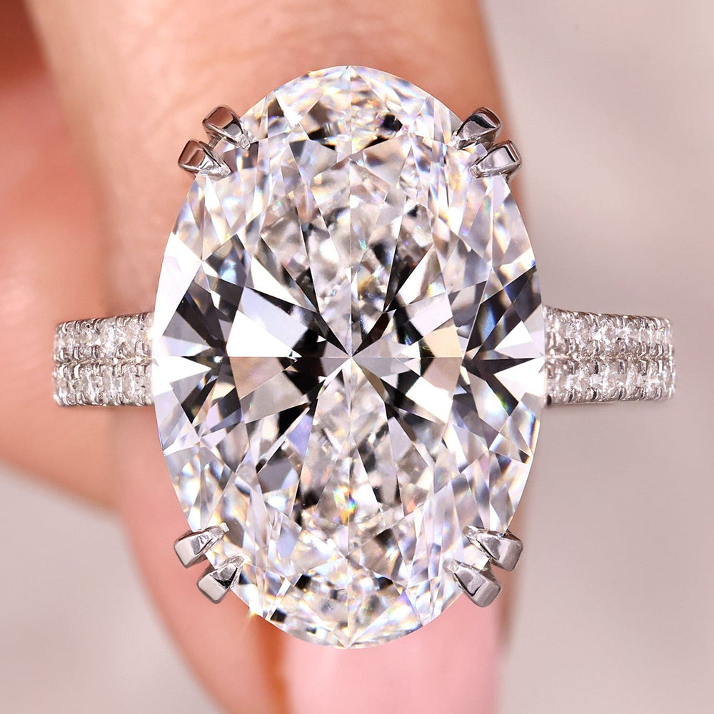 Oval diamond ring with cathedral setting and double row pave band.
