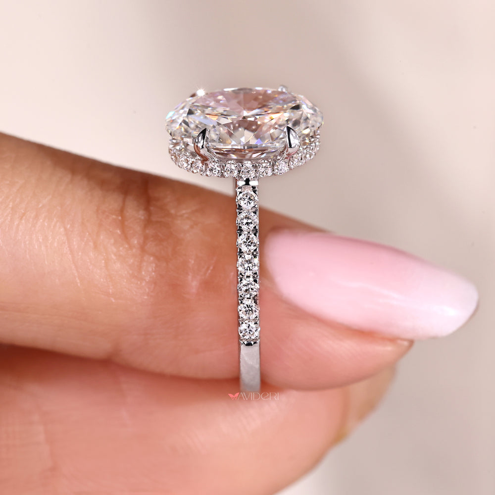 Hidden halo oval diamond engagement ring with pave band.
