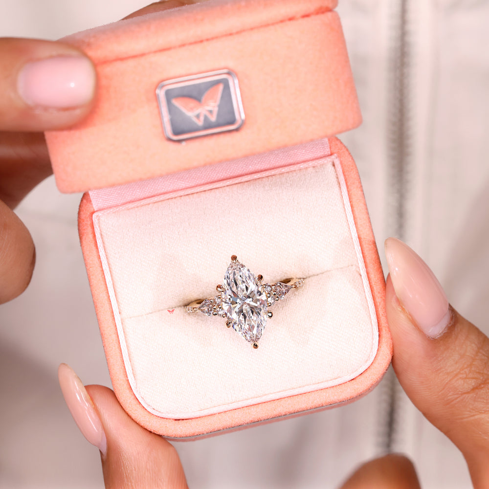 Tapered shank marquise ring with pave round diamond details.
