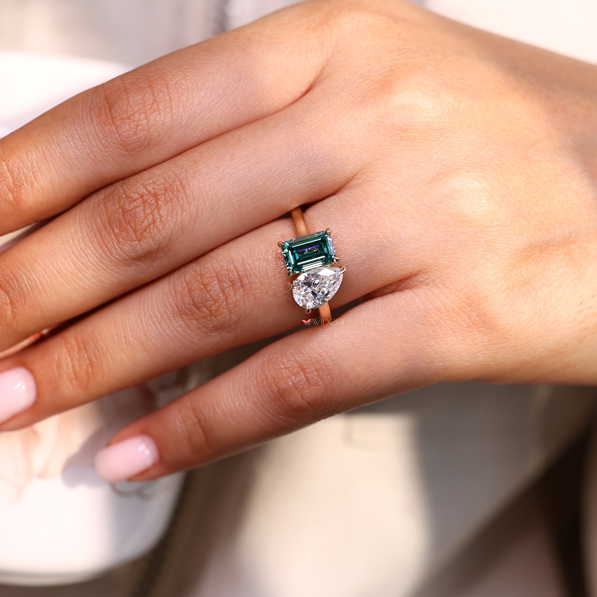 Green emerald cut engagement ring with pear stone design.